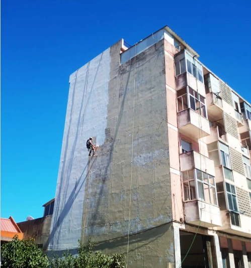 Home fazendo pintura na fachada do prédio